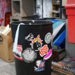 A garbage can is covered in Sike Style stickers in Phil Shafer's studio.