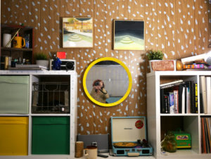 A bookcase wall in Seth's studio is filled with trinkets, books, and records, as well as two of Seth's pool paintings.