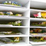 A file cabinet holds stacks of flower wreaths waiting to be shipped.