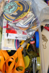 A pile of badges sit in a mismatched box in Luke's studio.