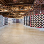 A corridor or Luke's quilts flow through an exhibition space.