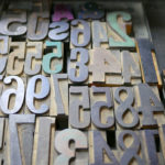 A tray full of letterpress numbers are tinted with the colors of recently used ink.